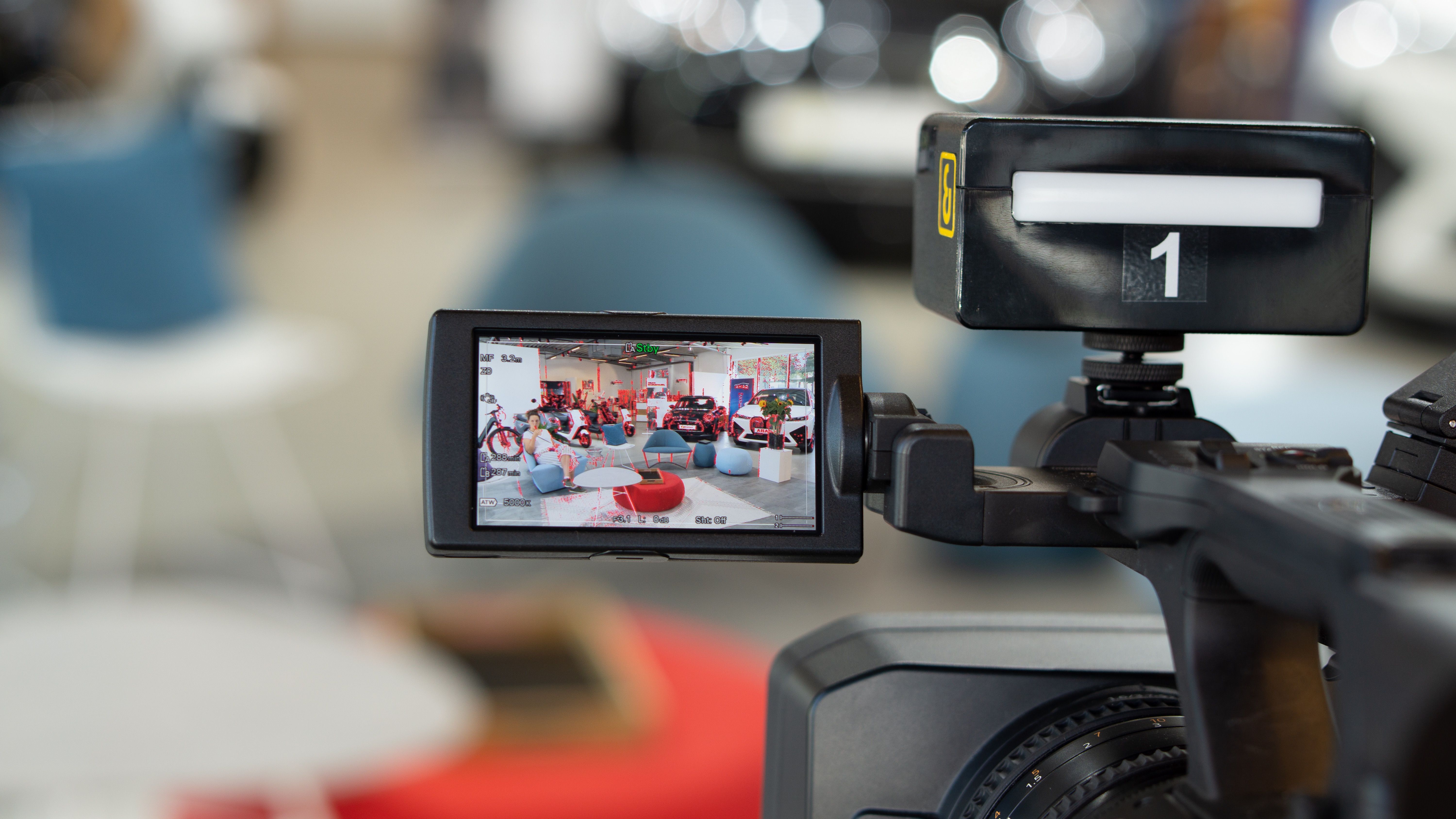 Film Kamera gerichtet auf Talk Situation im Hintergrund ein MINI Cooper SE und ein iX