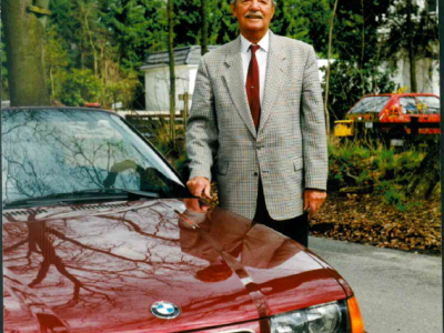 Herr an rotem BMW auf Straße